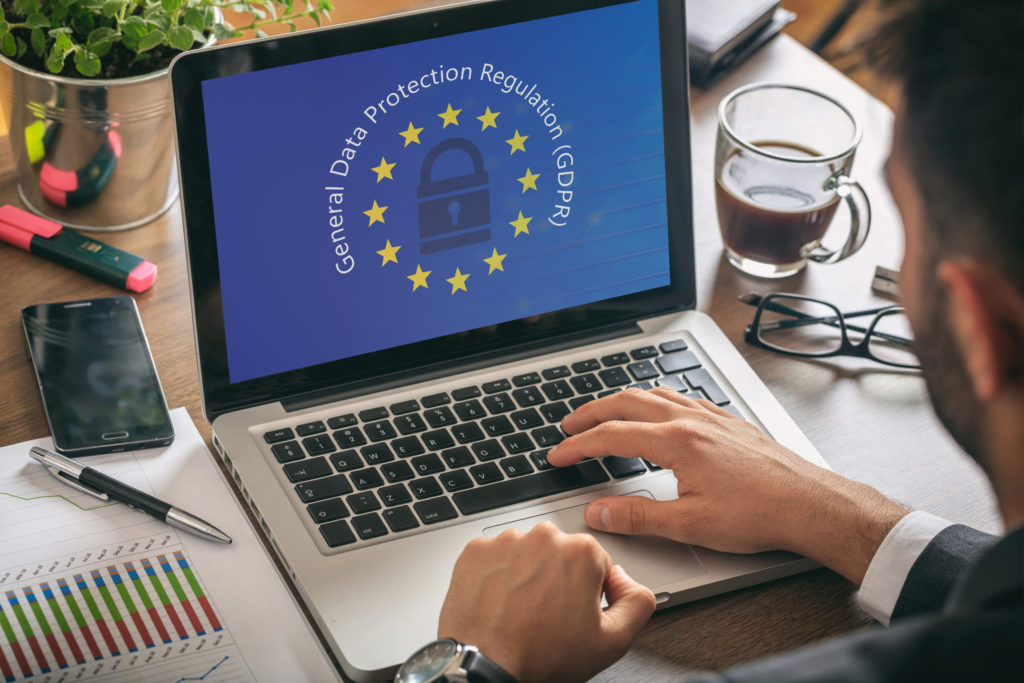 EU GDPR. Man working with a computer, General Data Protection Regulation and European Union flag on the screen